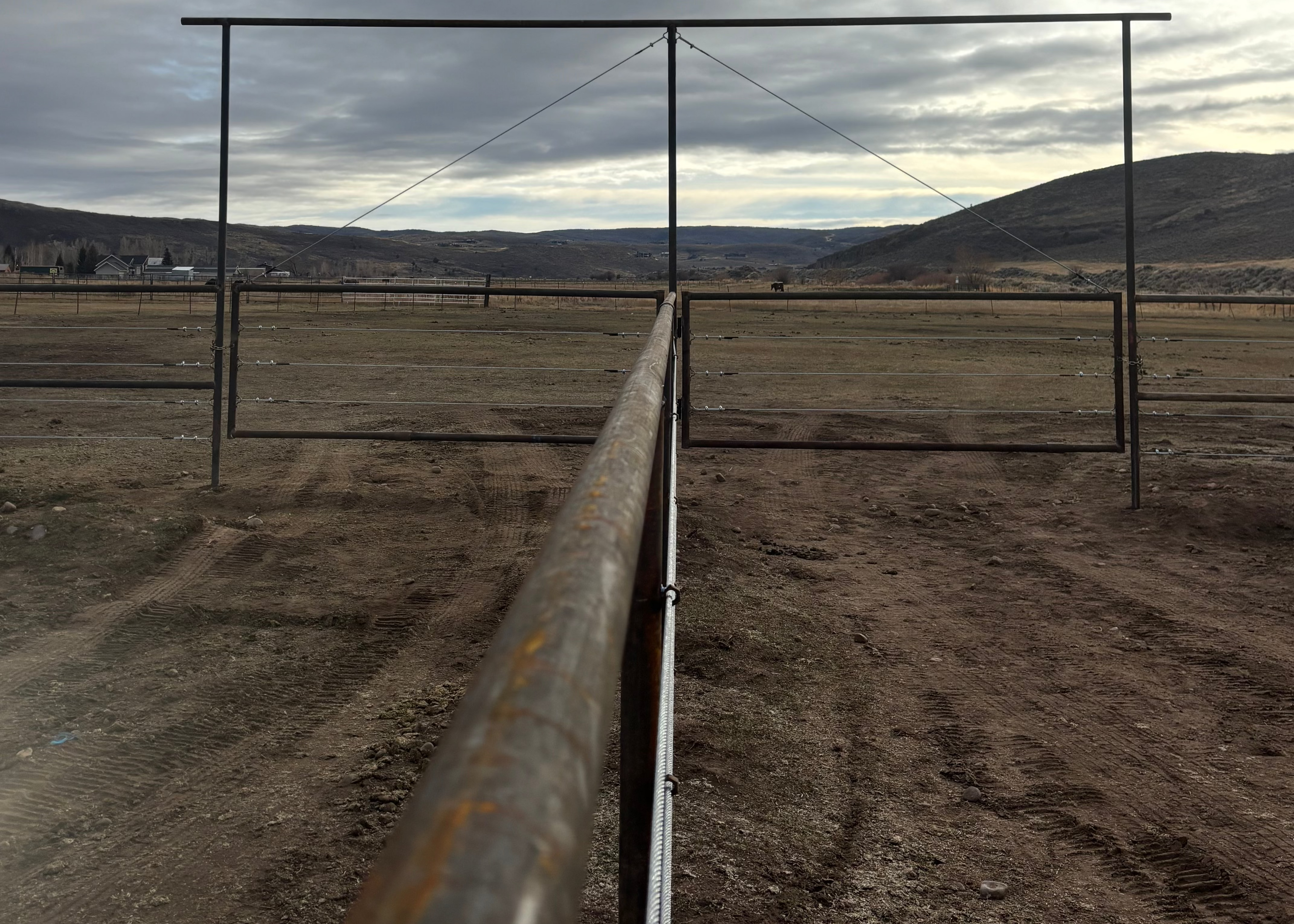 Long metal pipe running through a barren landscape with a cloudy sky.